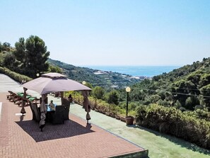 Terraço com área de estar ao ar livre, vista para o mar e um jardim ajardinado.
