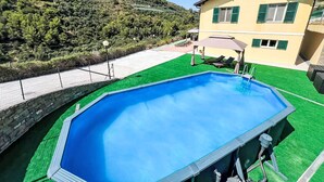 Una piscina con un muro de piedra y una casa con balcón.