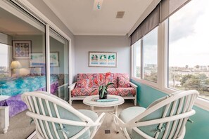 Ein Balkon mit einer Sitzecke, zwei Stühlen, einem kleinen Tisch und Blick auf die Stadt.