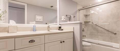A bathroom with a large mirror, a sink, a toilet, and a shower area.