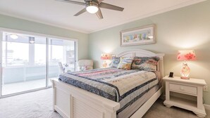 A bedroom with a bed, a ceiling fan, a nightstand with a lamp, and a large window. - 1200-406 - Standard Plus - Embrace Spectacular Water Views (Siesta Key)