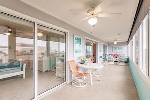 Uma varanda com mesa e cadeiras, um ventilador de teto e vista para a cidade.