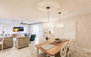 Ein modernes Wohnzimmer mit einer Couch, einem Esstisch mit Stühlen und einem an der Wand befestigten Fernseher.