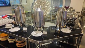 Una mesa de buffet con varios dispensadores de café y una variedad de platos.