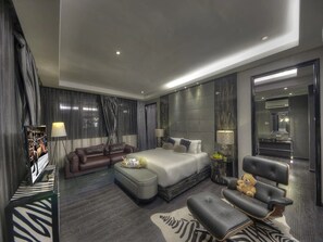 Een moderne hotelkamer met een groot bed, een bank, een stoel en een kleine tafel met een teddybeer.