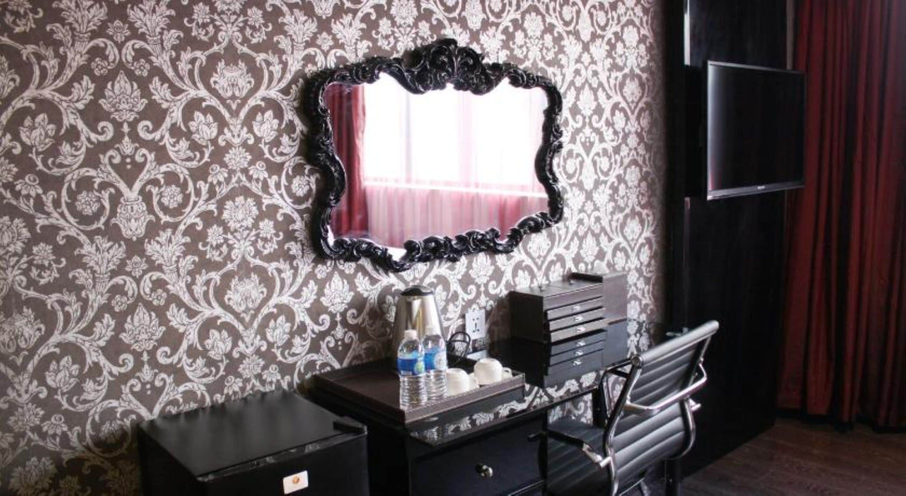 Una habitación con tocador, espejo, escritorio con cajones y una silla.