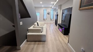 A modern living room with a sectional sofa, a flat-screen TV, and a fireplace.