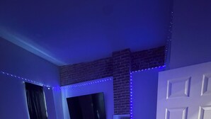 A bedroom with a bed, a TV mounted on the wall, and a door.