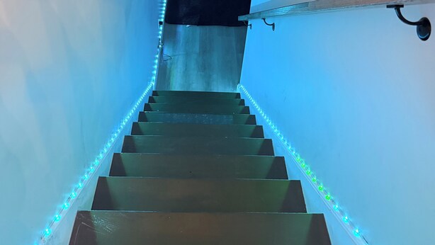 A staircase with blue LED lights along the steps and a black object at the top.