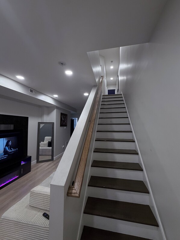 A modern staircase with a wooden handrail leading to a landing.