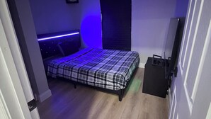 A bedroom with a bed, a dresser, and a door.