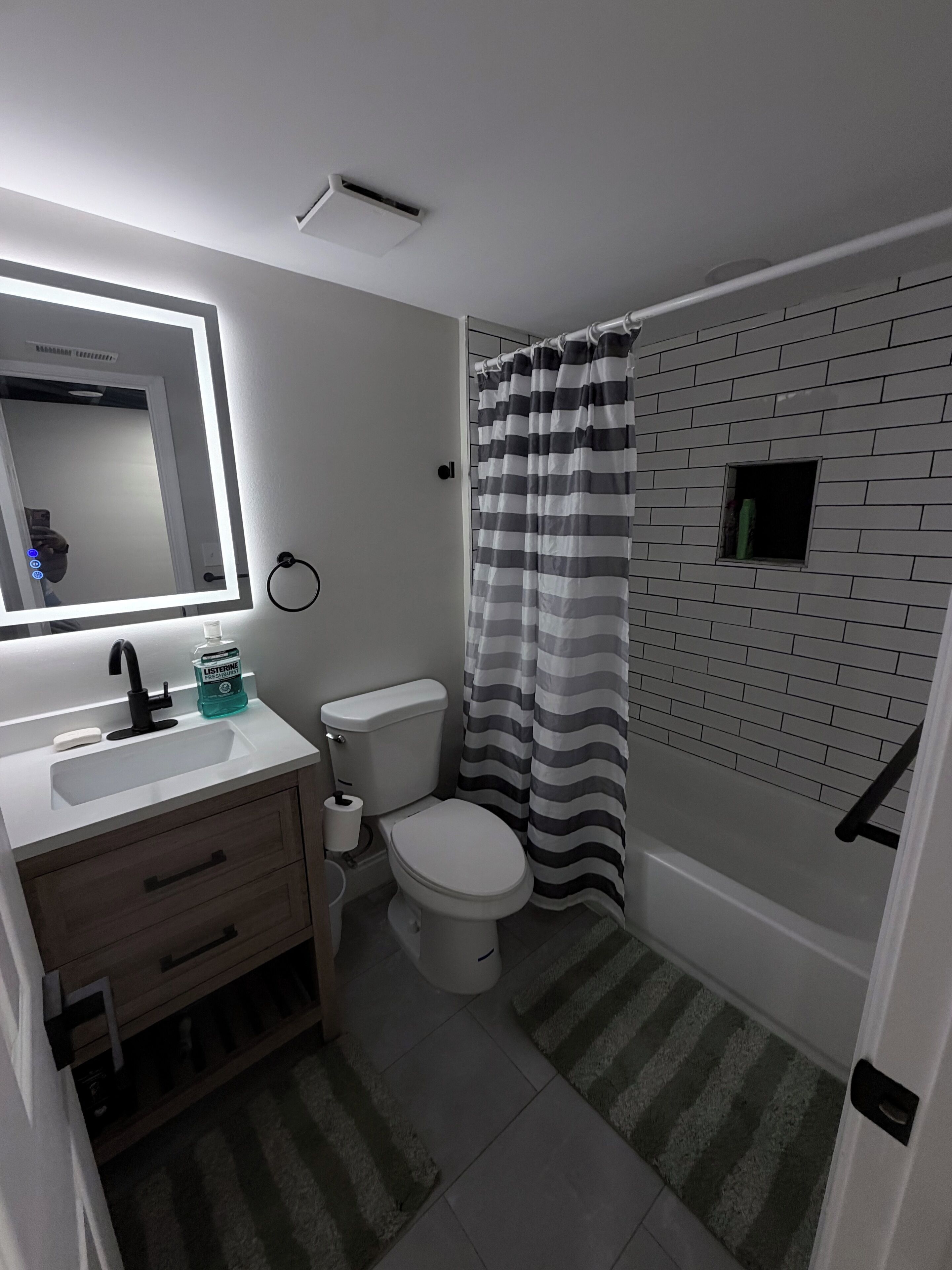 A bathroom with a white sink, mirror, toilet, and striped shower curtain.