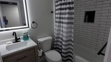 A bathroom with a white sink, mirror, toilet, and striped shower curtain.