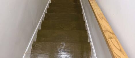Una escalera de madera con barandilla que conduce a una habitación con pared de mármol negro.