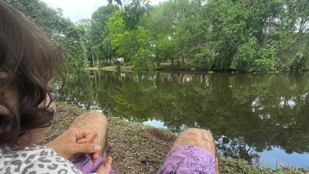 A person sitting by a body of water with trees in the background. -     Creekside Private Room & Bathroom  Fishing  Peaceful Retreat (Clute)