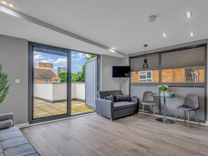A modern living room with a grey sofa, a small table, and a TV mounted on the wall. - Hoxton Residence by Interhome (Hoxton)
