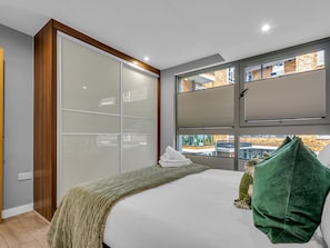 A bedroom with a bed, a large window, and a sliding door. - Hoxton Residence by Interhome (Hoxton)