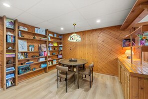 A cozy room with a wooden herringbone wall, a round table with chairs, and a bookshelf filled with books and decorative items. - 4-Bedroom Hot Tub Getaway Near Beaches & Wineries (Stevensville)