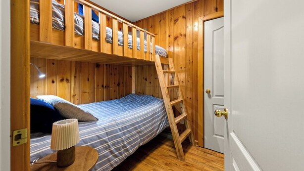 Ein Stockbett mit einer Leiter, ein Nachttisch mit einer Lampe und eine weiße Tür.