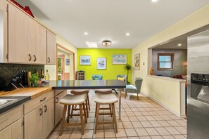 A kitchen with a central island, bar stools, and a refrigerator. - 4-Bedroom Hot Tub Getaway Near Beaches & Wineries (Stevensville)