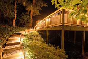 A wooden deck with steps leading up to it, surrounded by greenery. - 4-Bedroom Hot Tub Getaway Near Beaches & Wineries (Stevensville)
