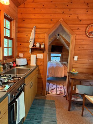Un intérieur de chalet chaleureux comprenant une cuisine, un coin repas et une chambre avec une mezzanine.