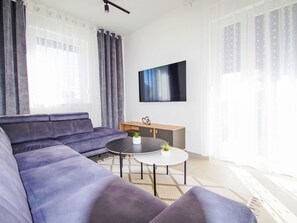 A modern living room with a sectional sofa, a coffee table, and a flat-screen TV mounted on the wall. - Charming 3-Bedroom Riviera by Interhome (Nedescina)