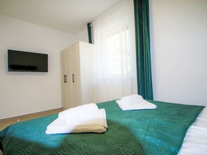 Een hotelkamer met een bed, een aan de muur bevestigde televisie en een kledingkast.