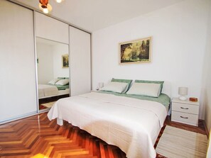 Une chambre à coucher avec un lit, une table de chevet, une lampe, un tableau et une porte coulissante.