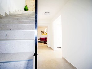 Una escalera conduce a una sala de estar con un sofá rojo y un cuadro en la pared.