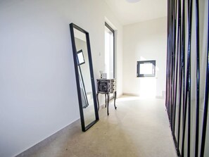 A hallway with a large mirror, a small table with a vase, and a window with blinds. - Stara Hiža by Interhome (Valbandon)