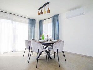 Een eetgedeelte met een ronde tafel, zes stoelen en een plafondlamp.