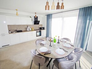 A modern kitchen with white cabinets, a dining table set for four, and pendant lighting. - Stara Hiža by Interhome (Valbandon)