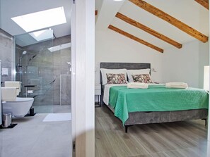 Een moderne slaapkamer met een groot bed, een douche en een dakraam.