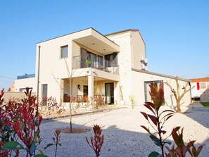 Ein zweistöckiges Gebäude mit Balkon, einem kleinen Kiesgarten und blauem Himmel.