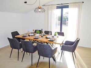 A dining area with a wooden table set for six, surrounded by six grey chairs. - Poli Nona by Interhome (Valbandon)