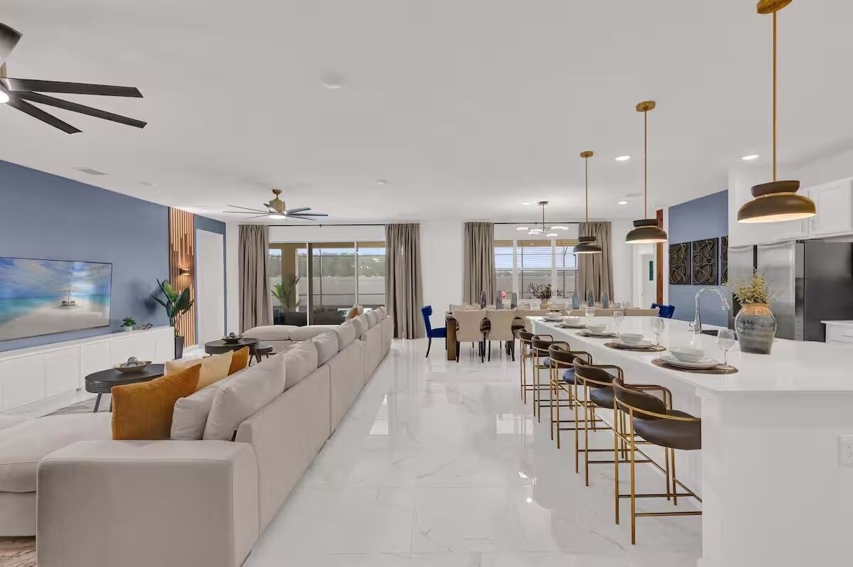 A modern kitchen with a central island, bar stools, and pendant lighting.