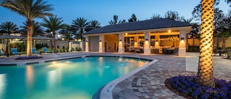 Una piscina con indicador de profundidad de 1,2 metros, rodeada por una terraza con mobiliario exterior y palmeras.