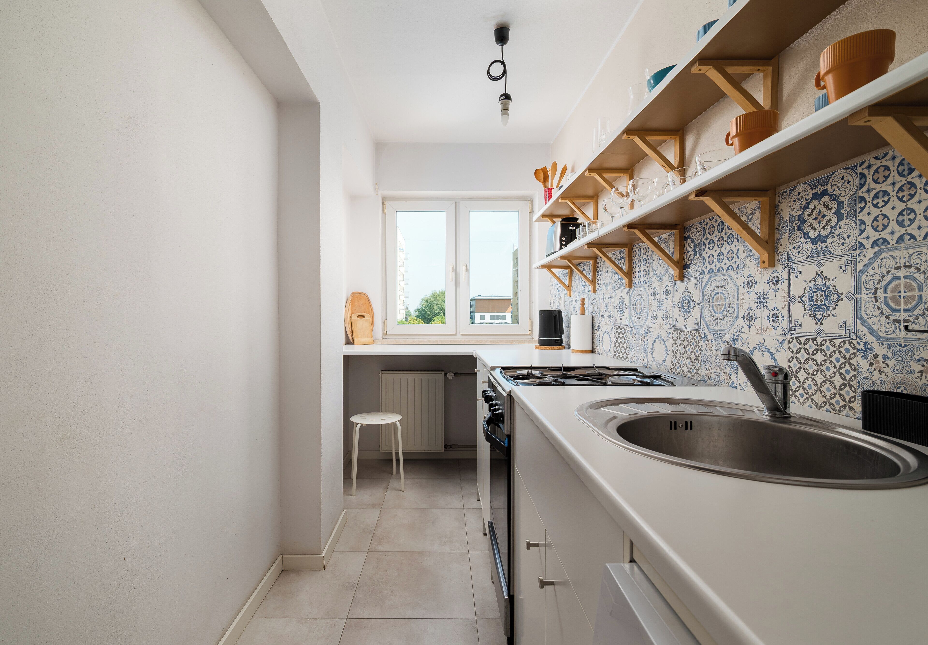 Una cocina estrecha con ventana, estufa y lavabo.