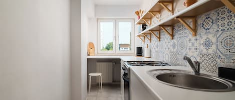 Una cocina estrecha con ventana, estufa y lavabo.