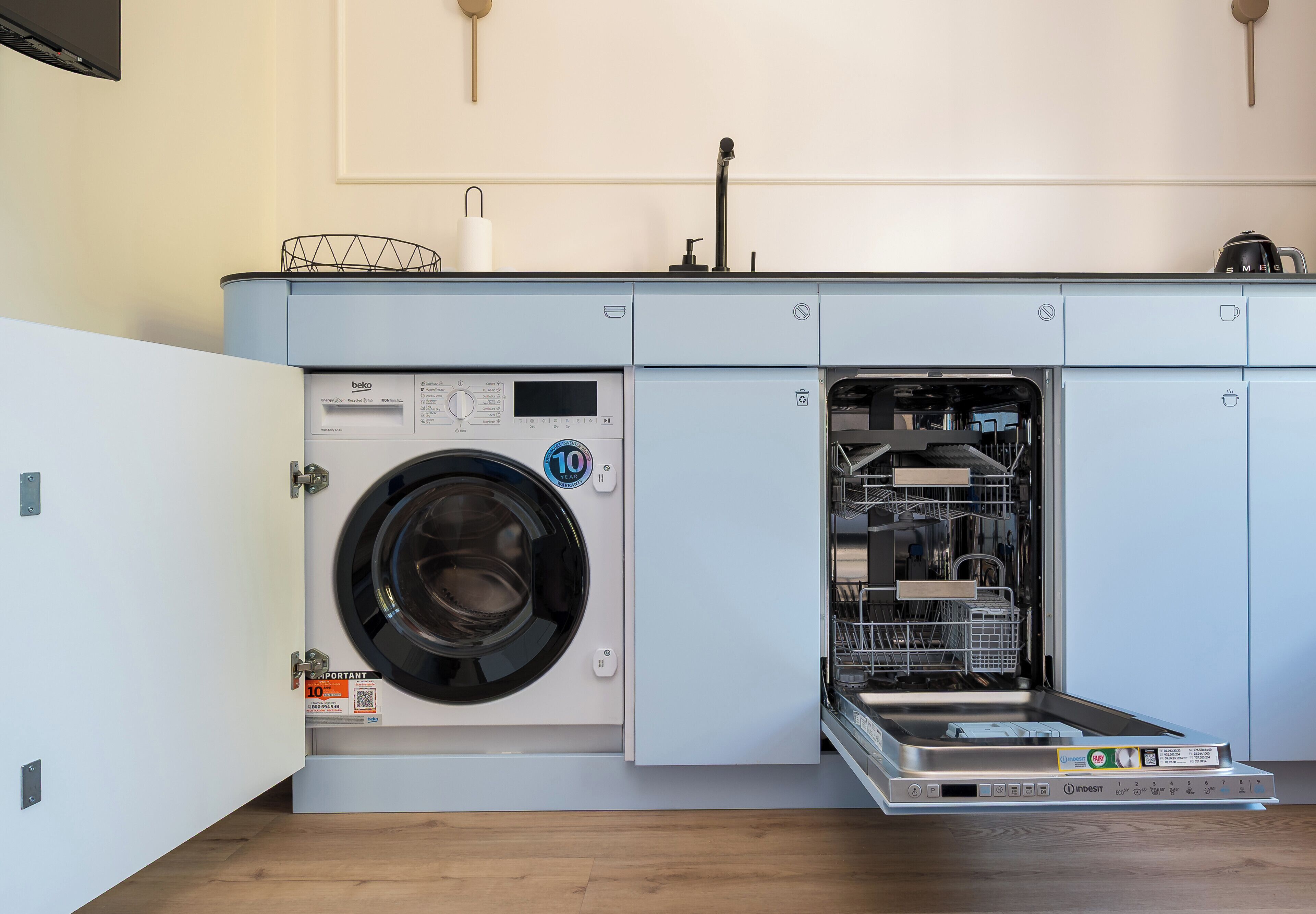A compact, modern laundry room with a front-loading washing machine and a built-in dishwasher.