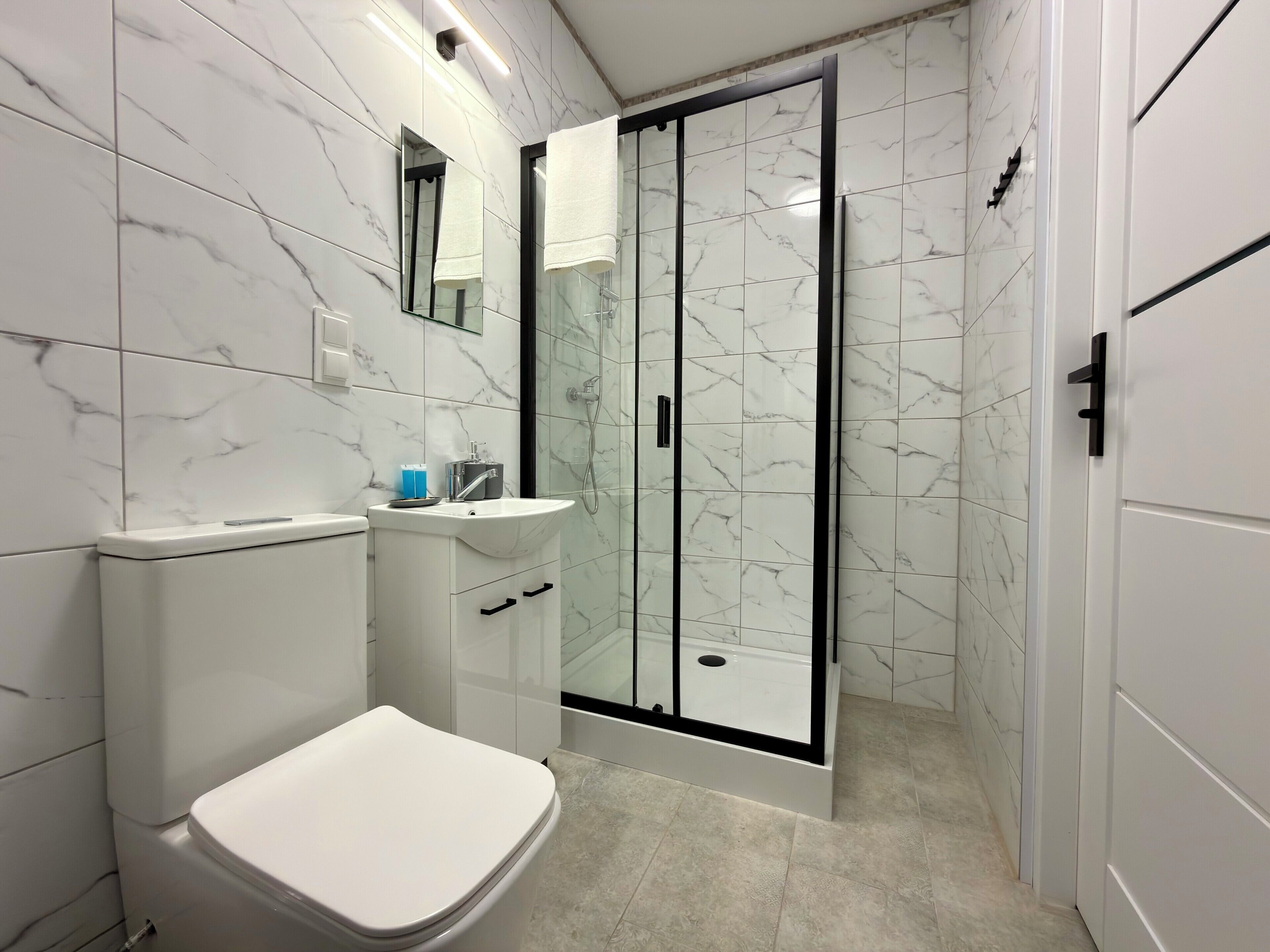A bathroom with a toilet, sink, and glass shower enclosure.