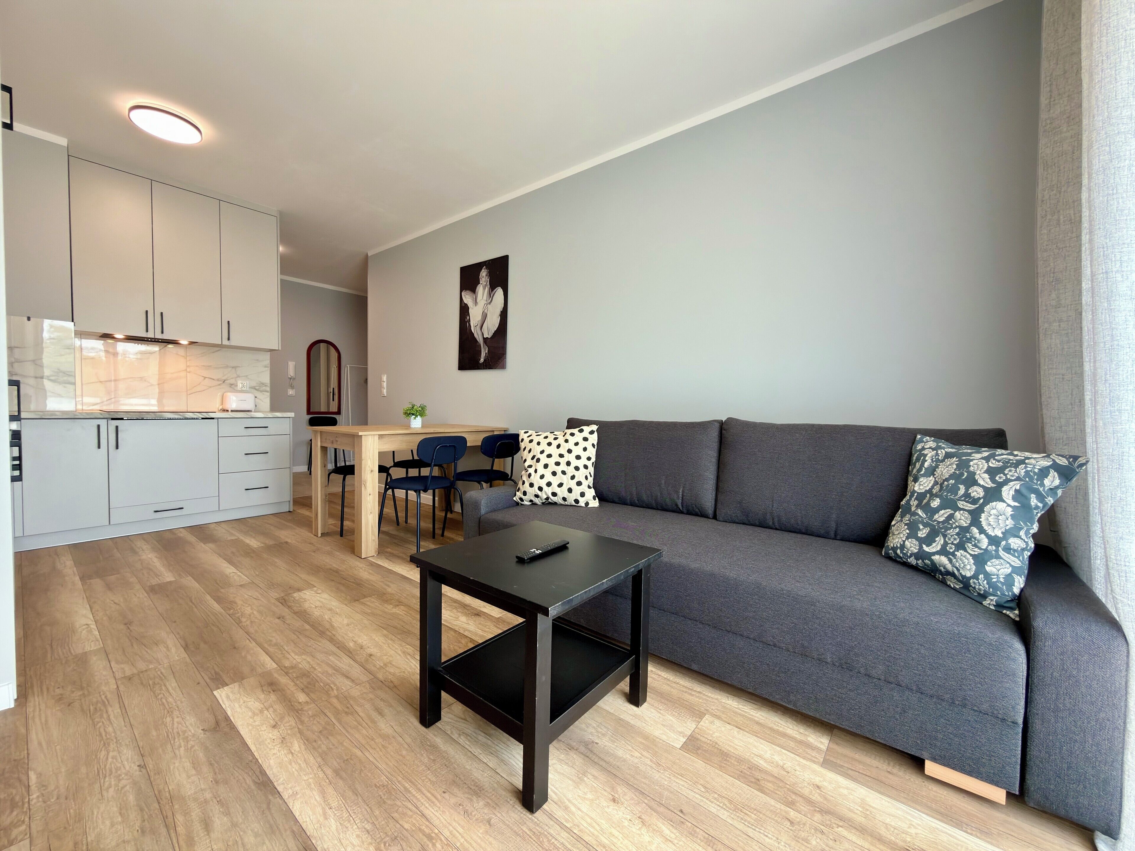 Um espaço de estar moderno, com sofá, mesa de centro e área de jantar com cadeiras.