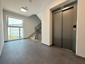 An interior space with a staircase, an elevator, and a large window. - Aleja Platanowa Superior Apartment (Wrocław)