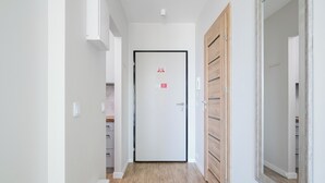 Ein Flur mit einer weißen Tür, Holzboden und einem Spiegel auf der rechten Seite.