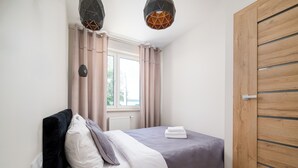 Ein Schlafzimmer mit einem Bett, Vorhängen, einem Heizkörper und einem Holzschrank.