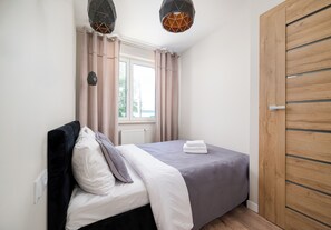 Ein Schlafzimmer mit einem Bett, Vorhängen, einem Heizkörper und einem Holzschrank.