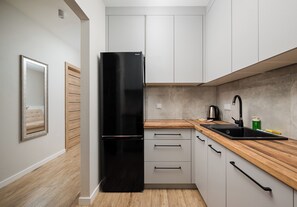 Eine moderne Küche mit weißen Schränken, einem schwarzen Kühlschrank, einer Holz Arbeitsplatte und einem schwarzen Spülbecken.