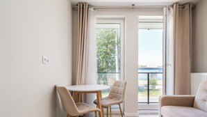 Ein modernes Wohnzimmer mit einem runden Tisch, zwei Stühlen, einem Sofa und einem Balkon mit Vorhängen.