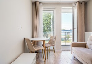 Ein modernes Wohnzimmer mit einem runden Tisch, zwei Stühlen, einem Sofa und einem Balkon mit Vorhängen.